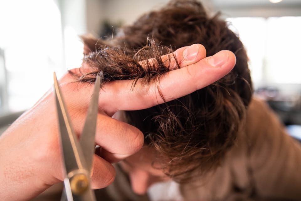 Manos de un peluquero cortando el pelo con tijeras.