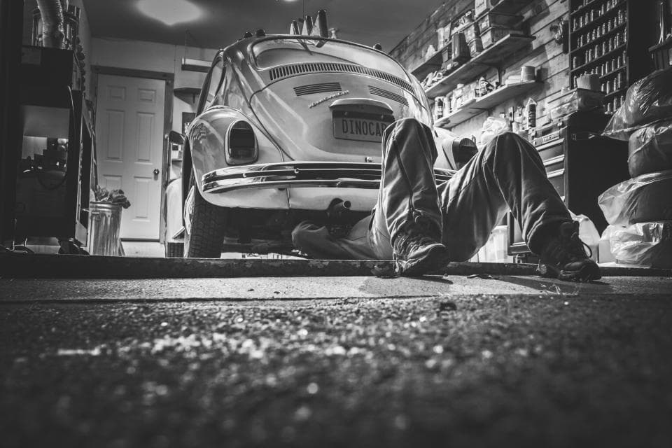 Un mecánico trabajando bajo un coche en un taller.