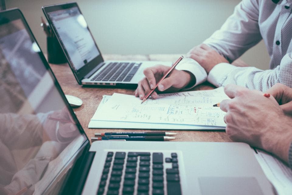 Dos personas repasando un plan de trabajo con portátiles sobre la mesa.